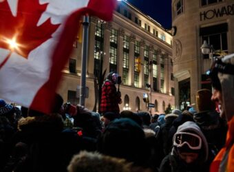 A man livestreams as protesters gather and party on Kent Street after police cleared Wellington Street, previously occupied by demonstrators in Ottawa on Feb. 19, 2022.